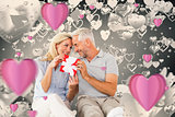 Composite image of happy couple sitting and holding present