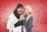Composite image of happy couple in winter fashion holding mugs