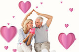 Composite image of happy couple sitting and sheltering piggy bank