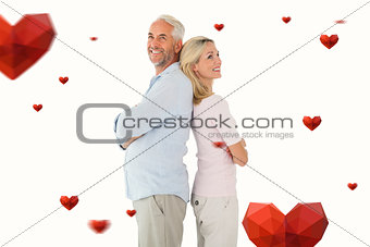 Composite image of smiling couple standing leaning backs together