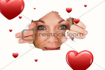 Composite image of woman looking through torn paper