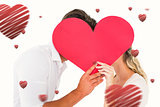Composite image of attractive young couple kissing behind large heart