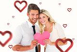 Composite image of attractive young couple holding pink heart