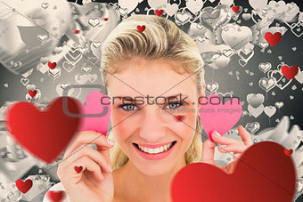 Composite image of attractive young blonde holding little hearts