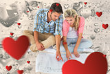 Composite image of attractive young couple sitting looking at blueprint
