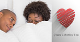 Composite image of happy couple lying in bed under the duvet