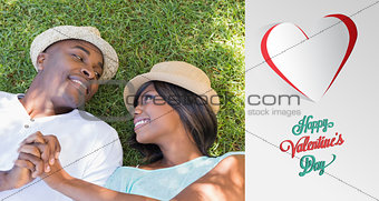 Composite image of happy couple lying in garden together on the grass