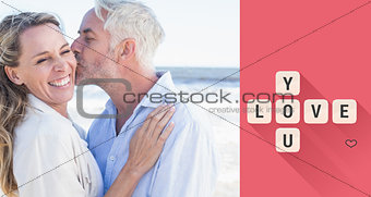 Composite image of man kissing his smiling partner on the cheek at the beach