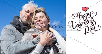 Composite image of carefree couple hugging in warm clothing