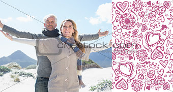 Composite image of carefree couple standing on the beach in warm clothing
