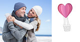 Composite image of attractive couple hugging on the beach in warm clothing