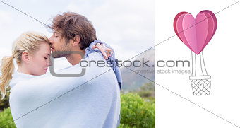 Composite image of cute affectionate couple standing outside wrapped in blanket