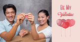 Composite image of happy couple holding house key and leaning on moving box
