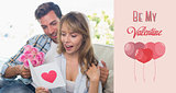 Composite image of loving couple with flowers and greeting card