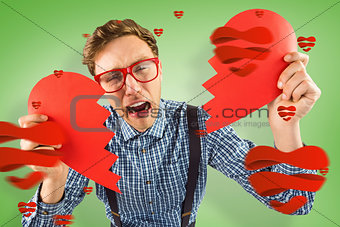 Composite image of geeky hipster holding a broken heart