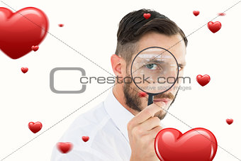 Composite image of geeky businessman looking through magnifying glass