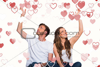 Composite image of happy young couple with hands raised