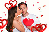 Composite image of woman kissing man as he holds heart