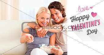 Composite image of cute couple watching tv while eating popcorn