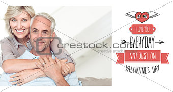 Composite image of smiling woman embracing mature man from behind on sofa
