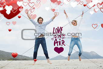 Composite image of cheerful young couple jumping at beach