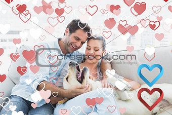 Composite image of happy couple petting their yellow labrador on the couch