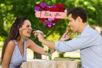 Composite image of couple feeding strawberries to each other at outdoor café