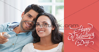 Composite image of attractive couple watching tv on the couch