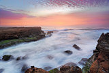 Stunning sunrise and ocean flows over tidal rocks