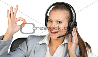 Businesswoman in headset making okay gesture