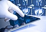 hand in medical glove touching modern digital tablet on x-ray images background