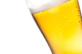detail of tilted glass of fresh beer with drops on white background