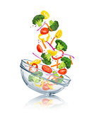 vegetables falling into a glass bowl on a white background. Conc