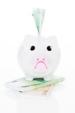 Sad piggy bank with money. Money does not make you happy.