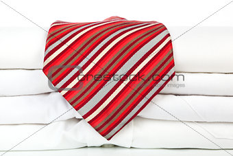 Pile of white shirts with red tie.