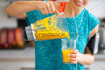 Close-up on fitness young woman pouring pumpkin smoothie in glas