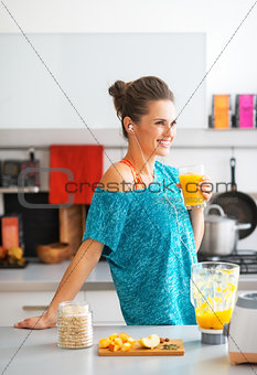 Happy fitness young woman with glass of pumpkin smoothie