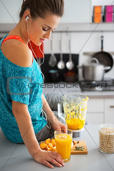 Fitness young woman with glass of pumpkin smoothie in modern kit