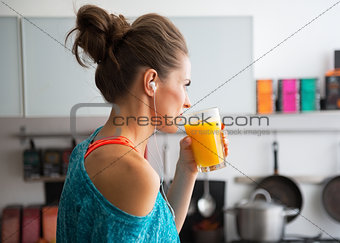 Fitness young woman drinking pumpkin smoothie in kitchen