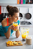 Fitness young woman with glass of pumpkin smoothie in kitchen