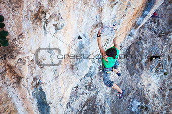 Rock climber holding on handhold while climbing cliff