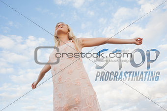 Composite image of young woman in summer dress stretching arms against sky