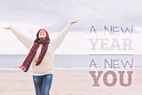 Composite image of woman in warm clothing stretching arms on beach