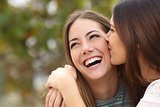 Woman laughing with perfect teeth while a friend is kissing her