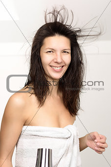 Attractive woman in a towel blow drying her hair