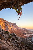 Male climber on overhanging rock against beautiful view of coast below