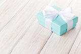 Gift box with bow over white wooden table