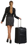 Businesswoman with wheeled travel bag makes step forward
