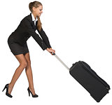 Businesswoman dragging heavy wheeled suitcase at utmost strain