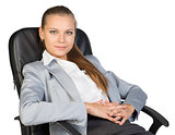 Businesswoman back in office chair, with hands clasped over her stomach